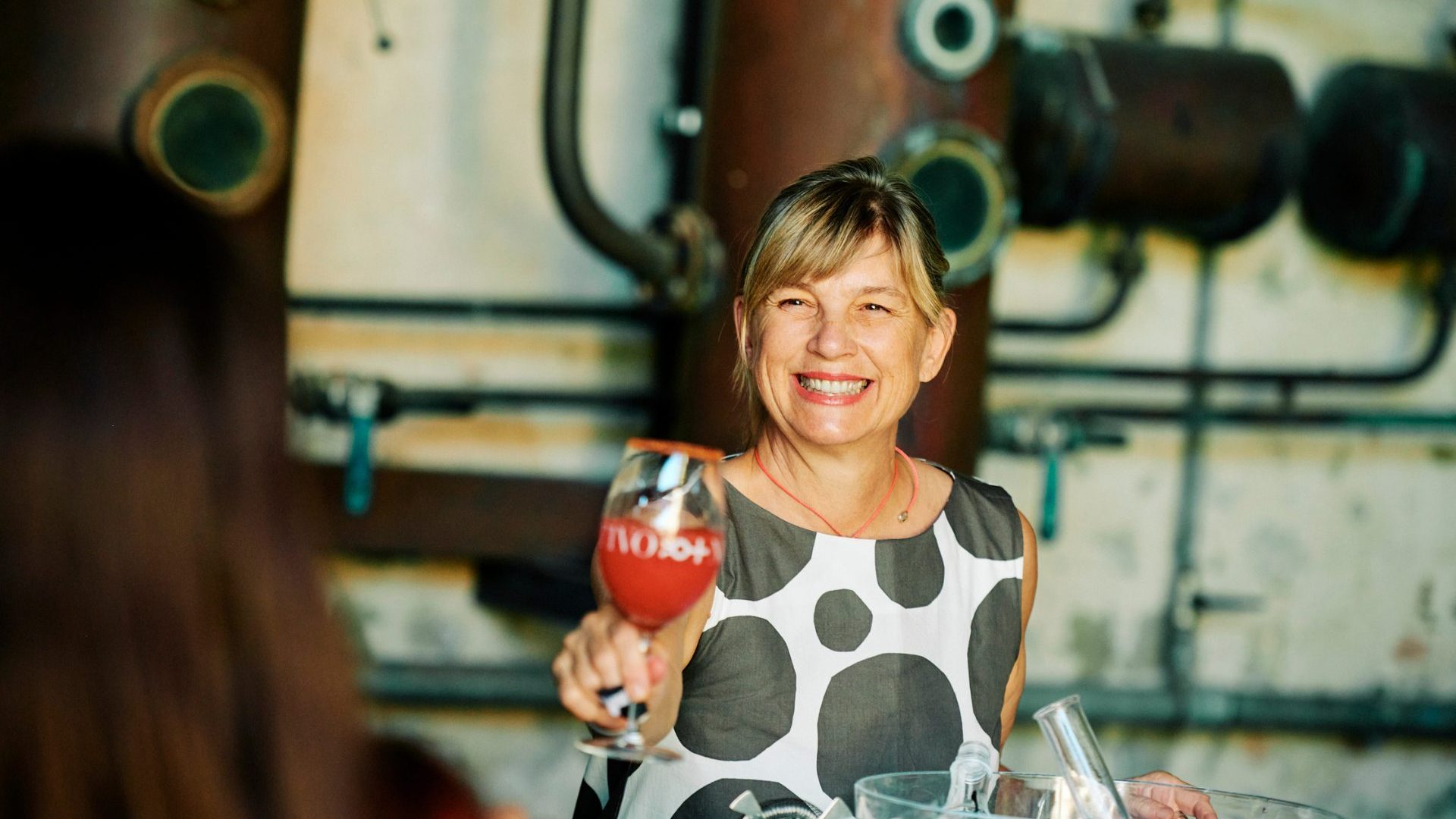 woman holds glass of wine out for a 'cheers'