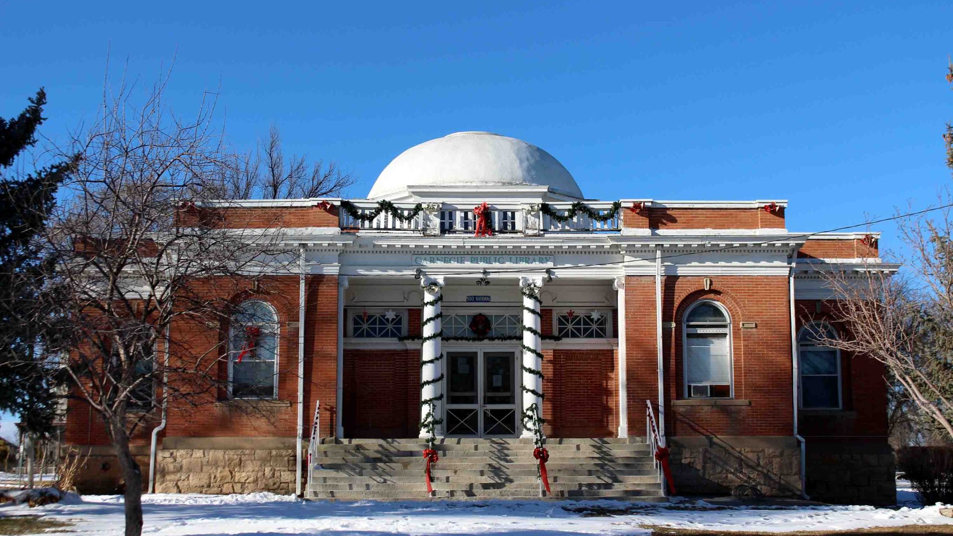 A building with terracotta coloured walls, a white dome and white pillars.