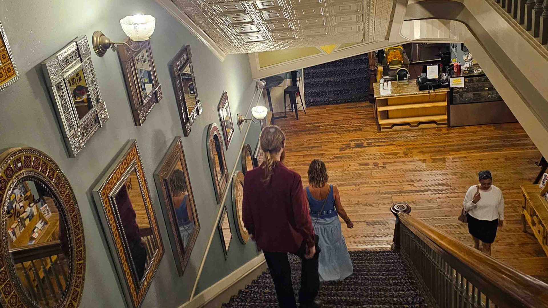 Two people walk down a stairwell inside a hotel.