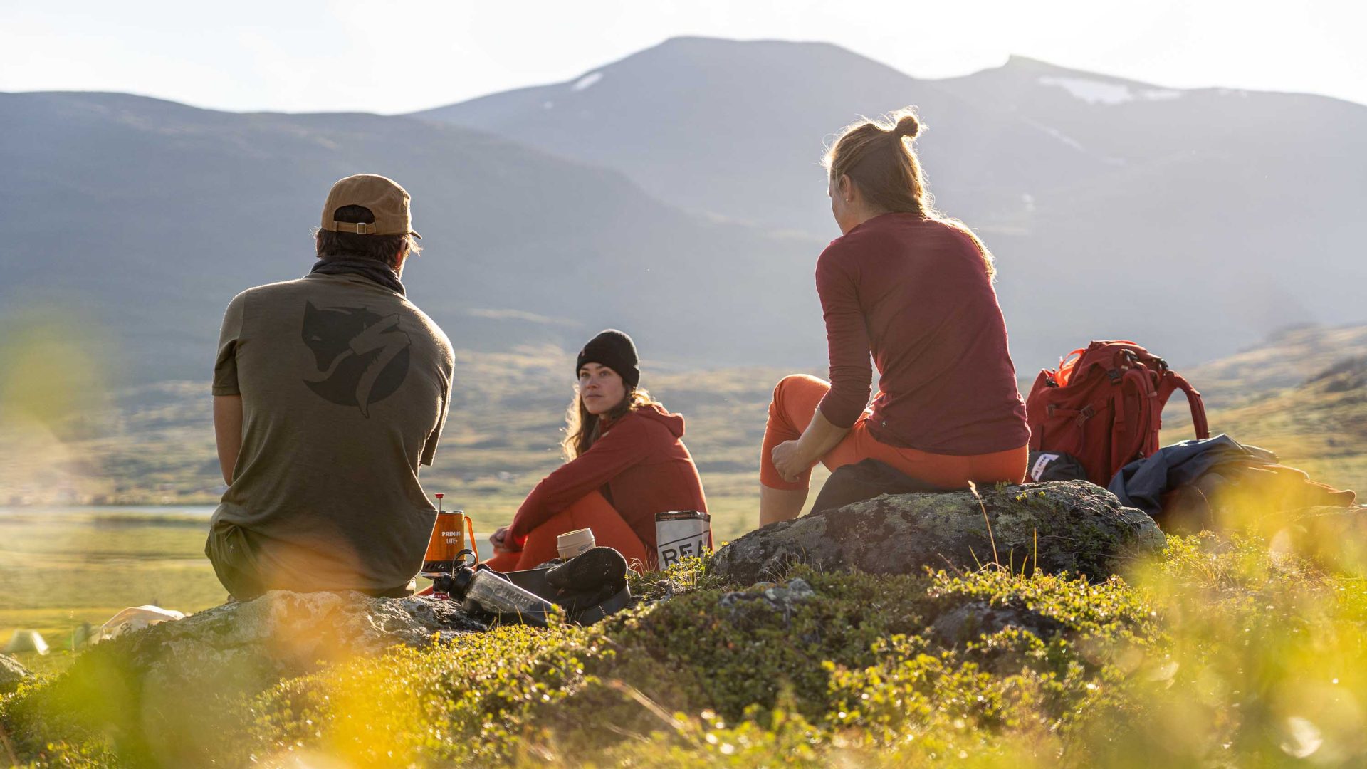 A woman sits with her friends and has a snack while hiking.