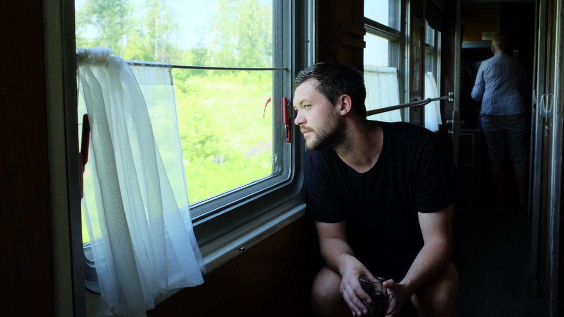 A man looks out the window of a moving train.