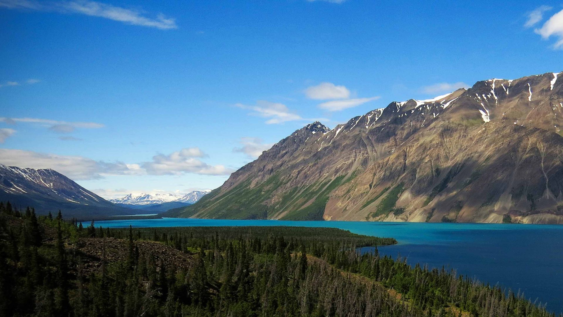 A turquoise lake below arid mountains.