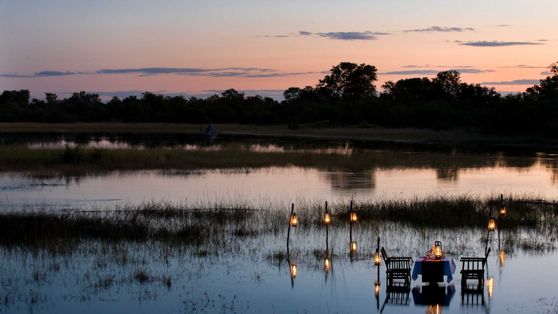 A table and two chairs sit in the water at dusk.