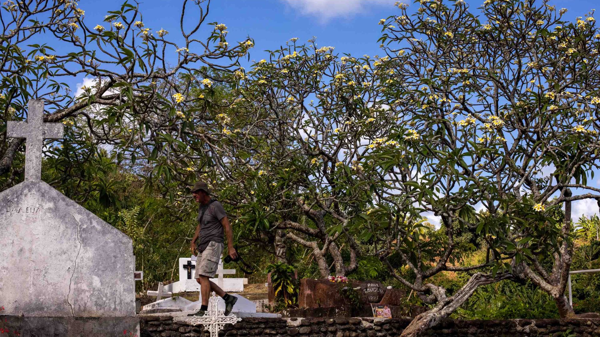 A man walks past a grave in a cemetery.