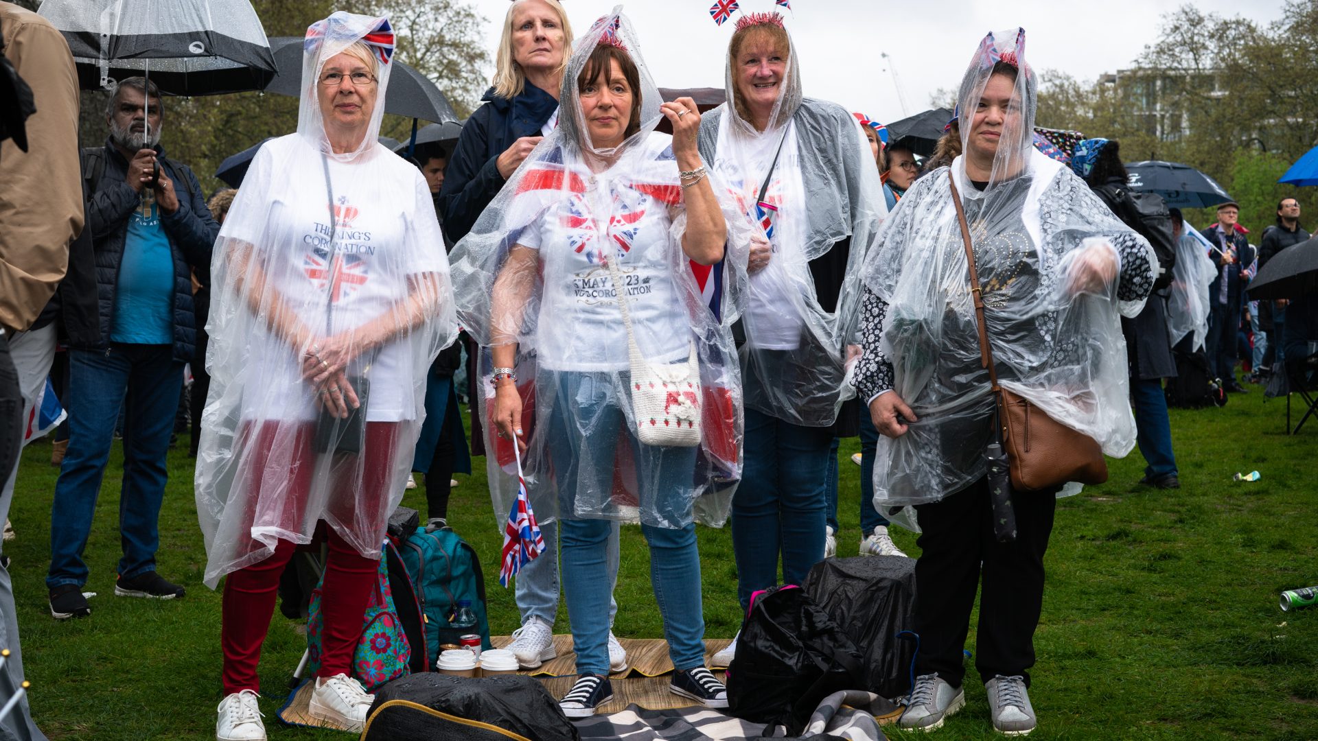 A group of five women with waterproof capes posing for a picture, three in Coronation T-shirts.