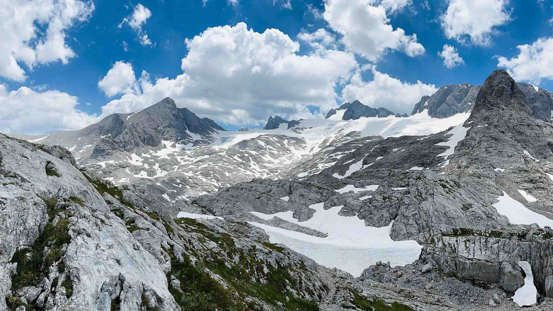 A panorama of a glacier with exposed rocks and snow.