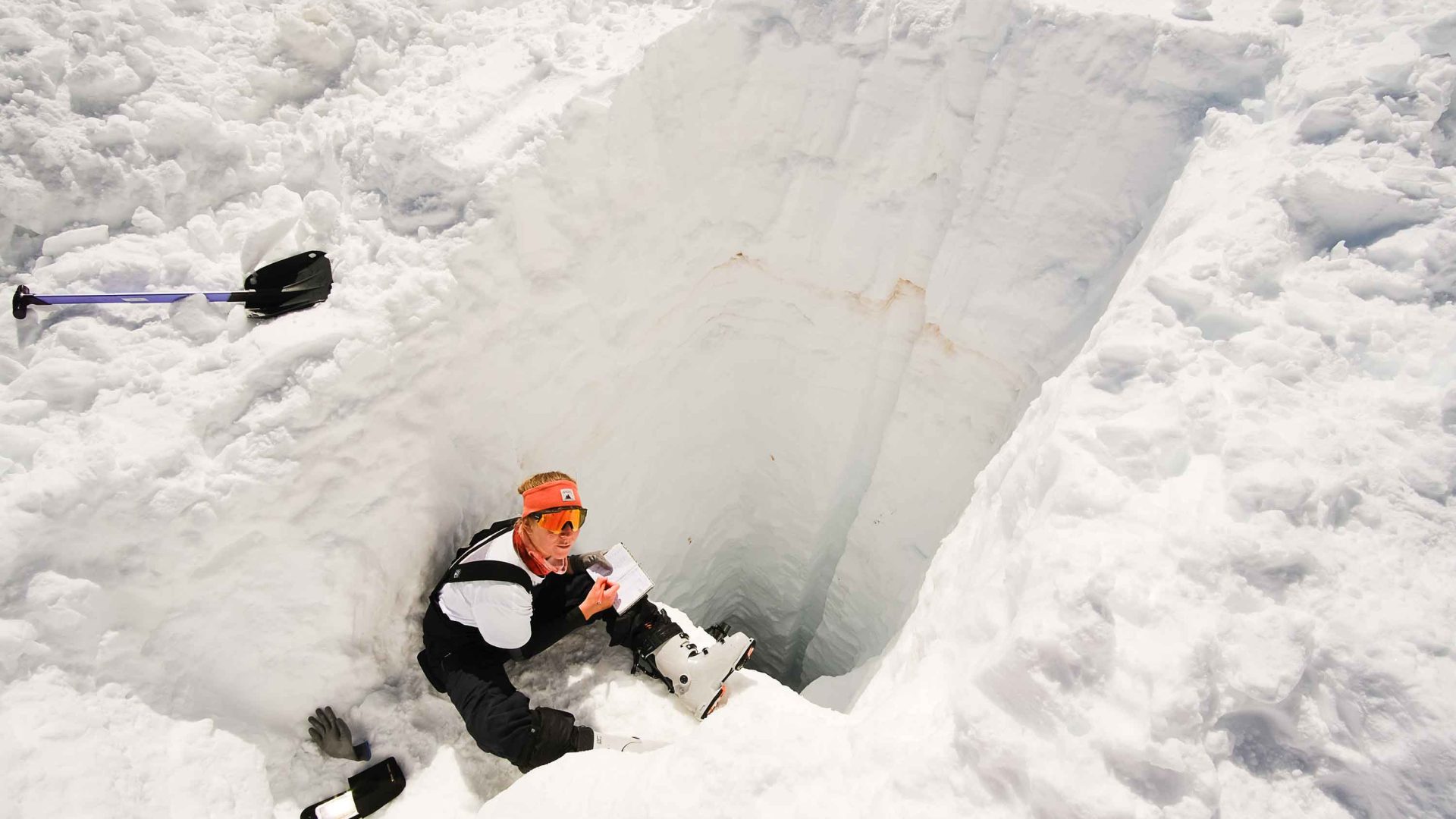 A man conducts a survey of a glacier while seated.