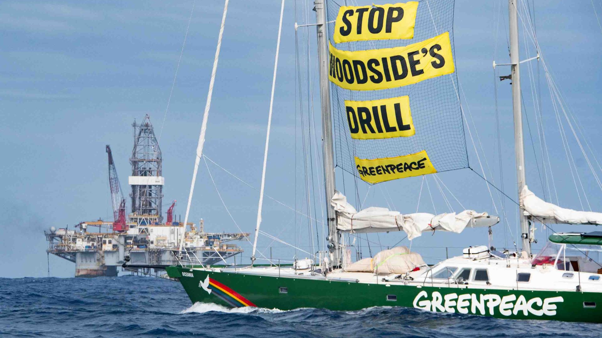 Crew aboard a Greenpeace vessel with the sign 'Stop Woodside's drill'.