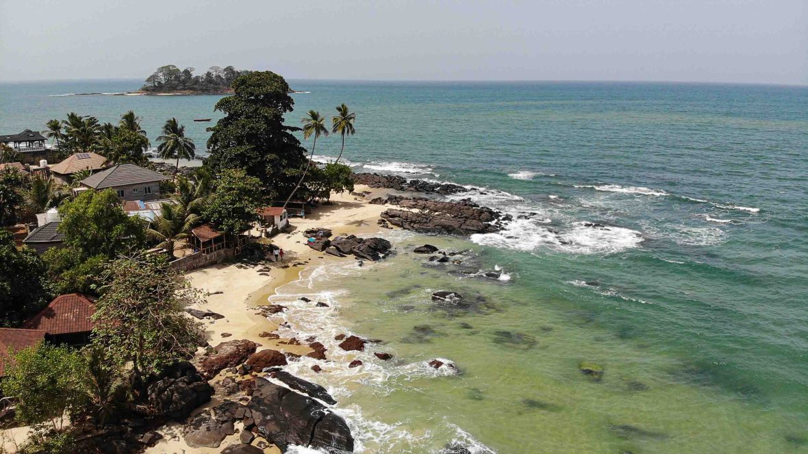 Looking down at the water, palms and island where KK learned to surf. There are a few small buildings near the shore.