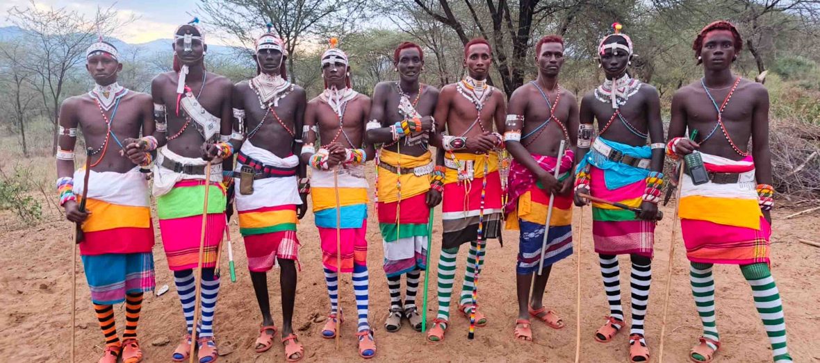 A line of warriors in traditional colorful clothes.