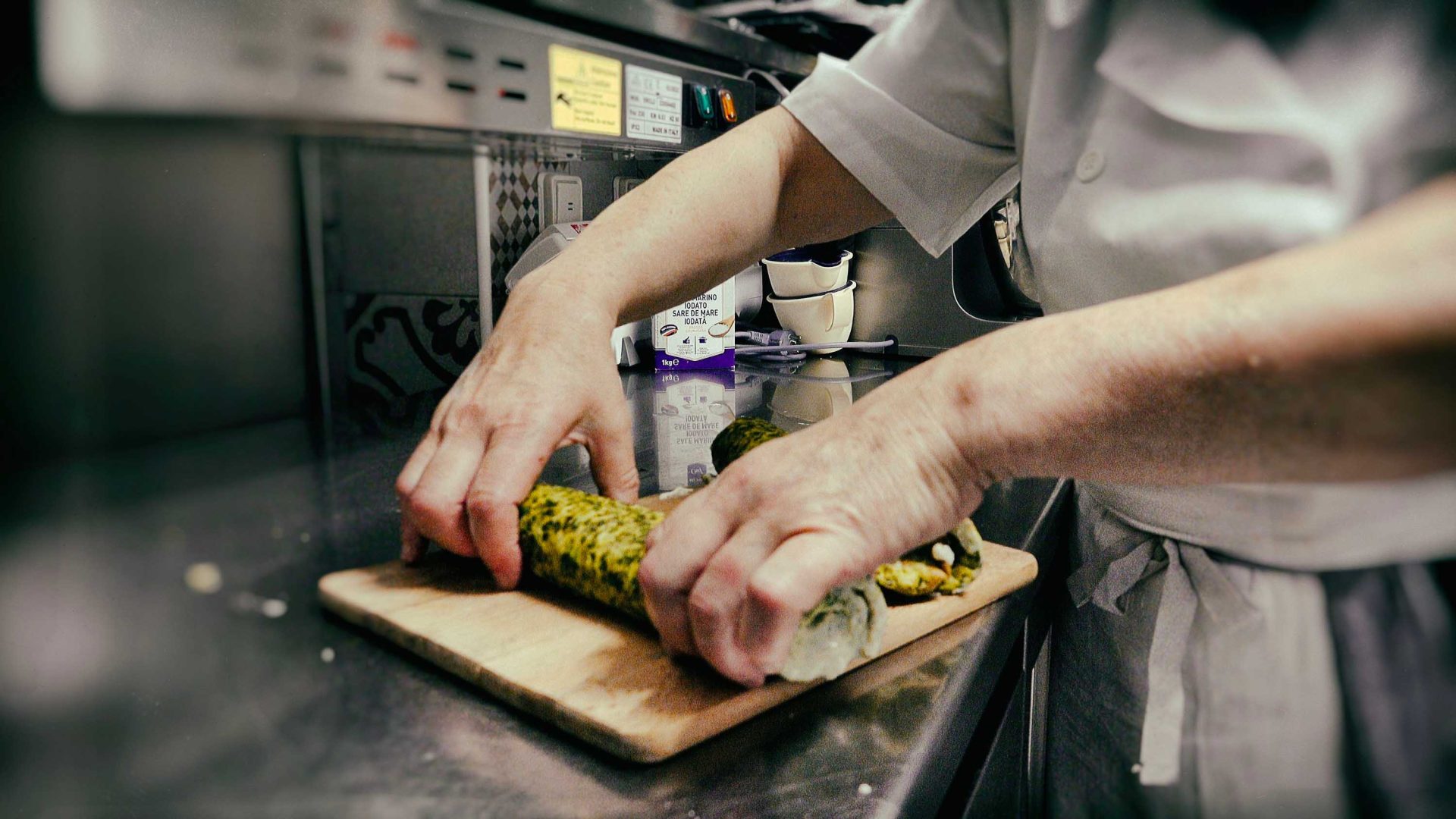 Hands roll up some green, yellow and white coloured food.