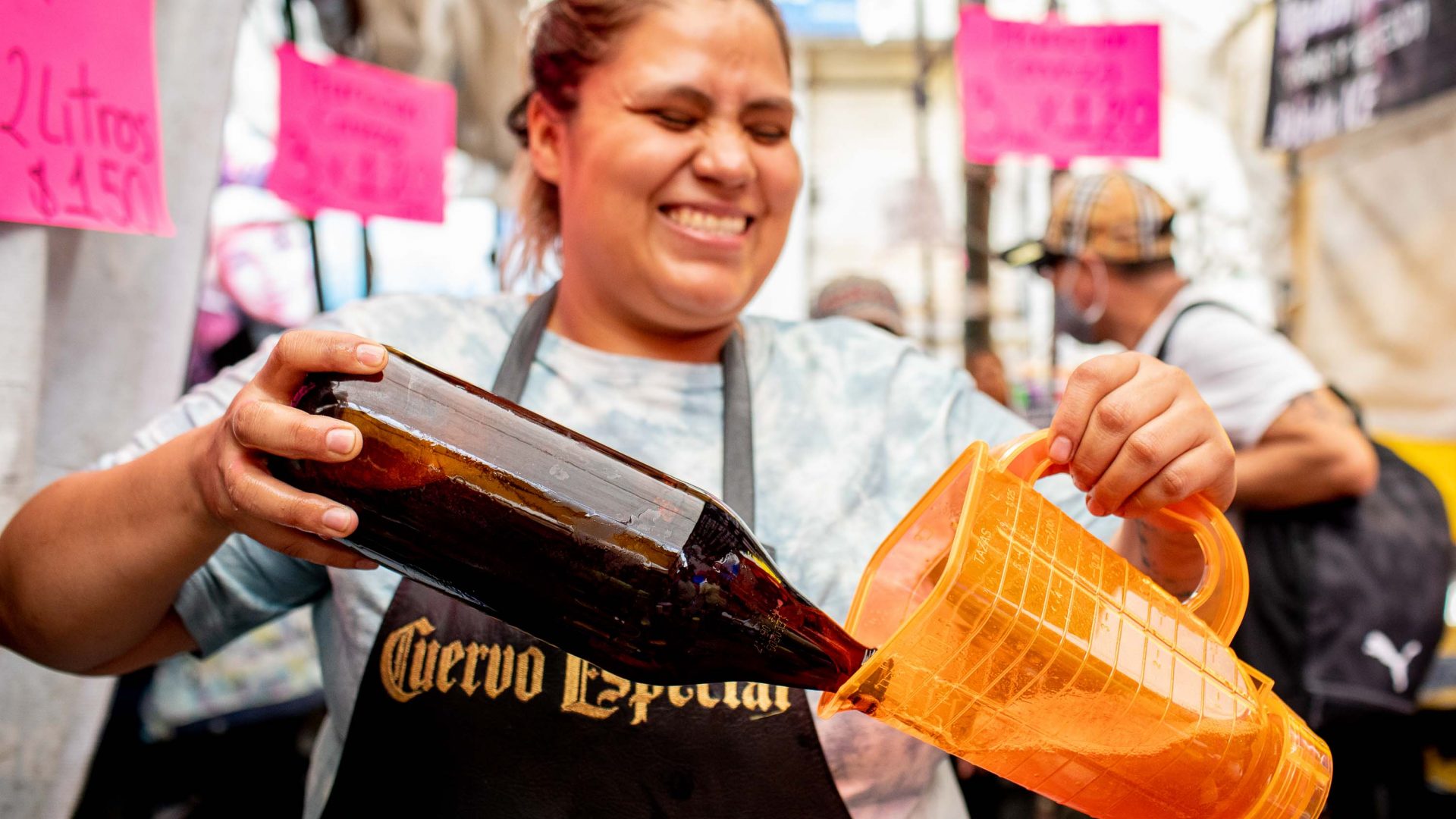 A woman pours beer into a jug.