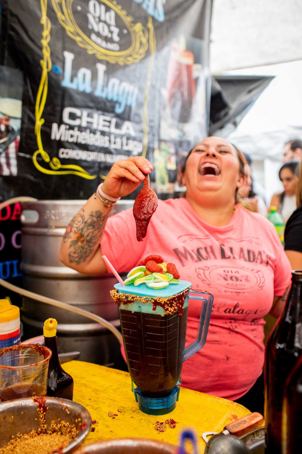 A woman laughs as she makes a michelada.