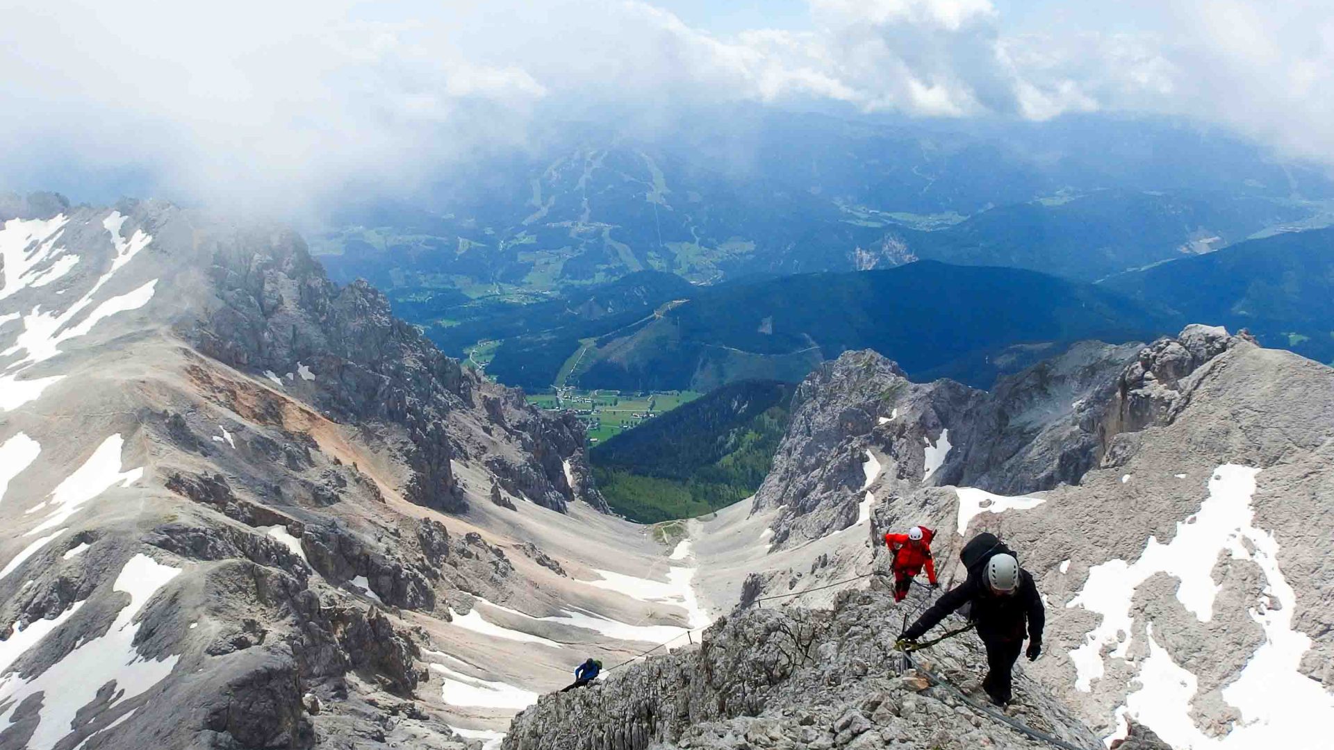 People climb a mountain with snow on it.