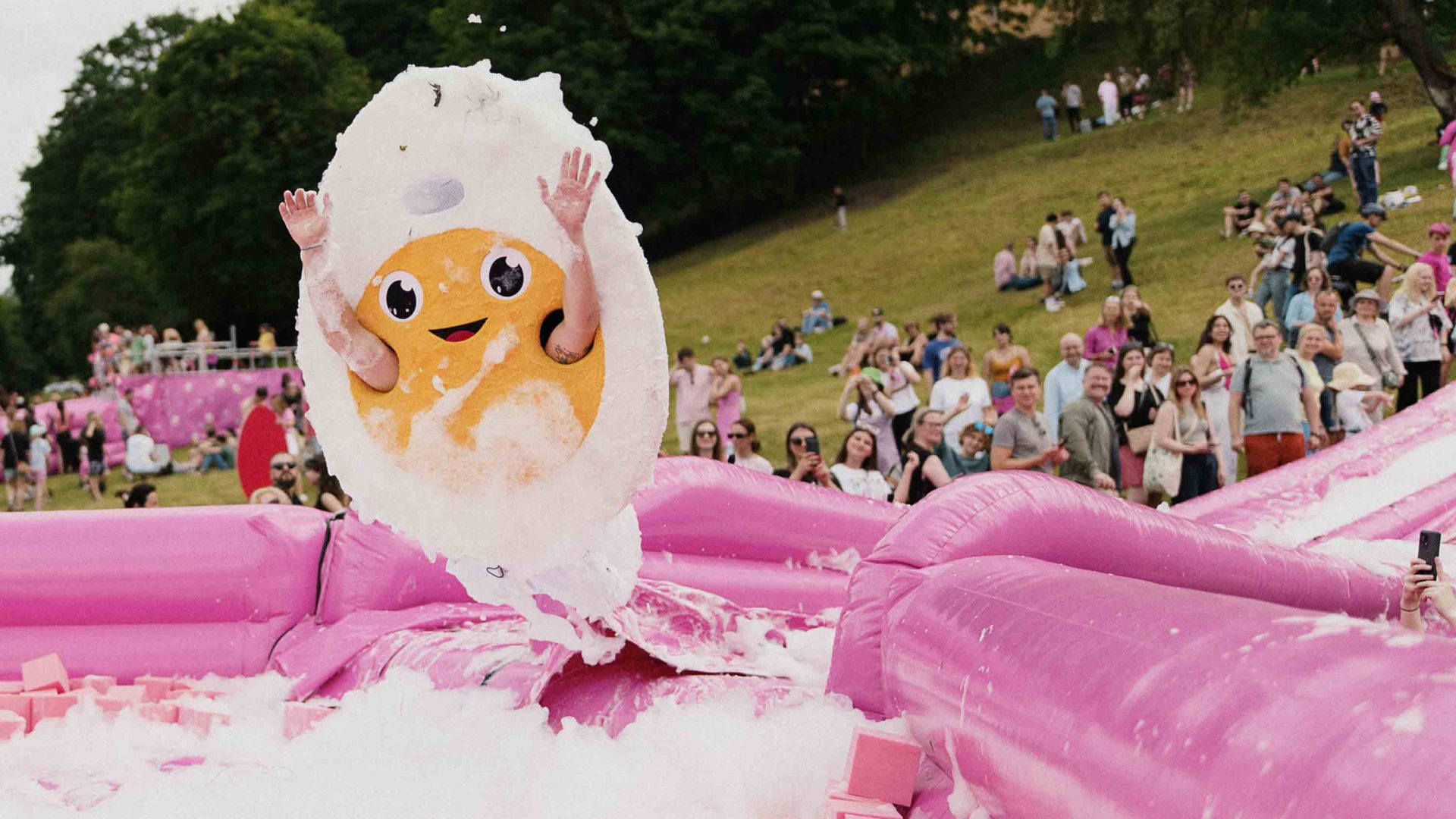 A person dressed as an egg slides down the slide at the pink soup festival.