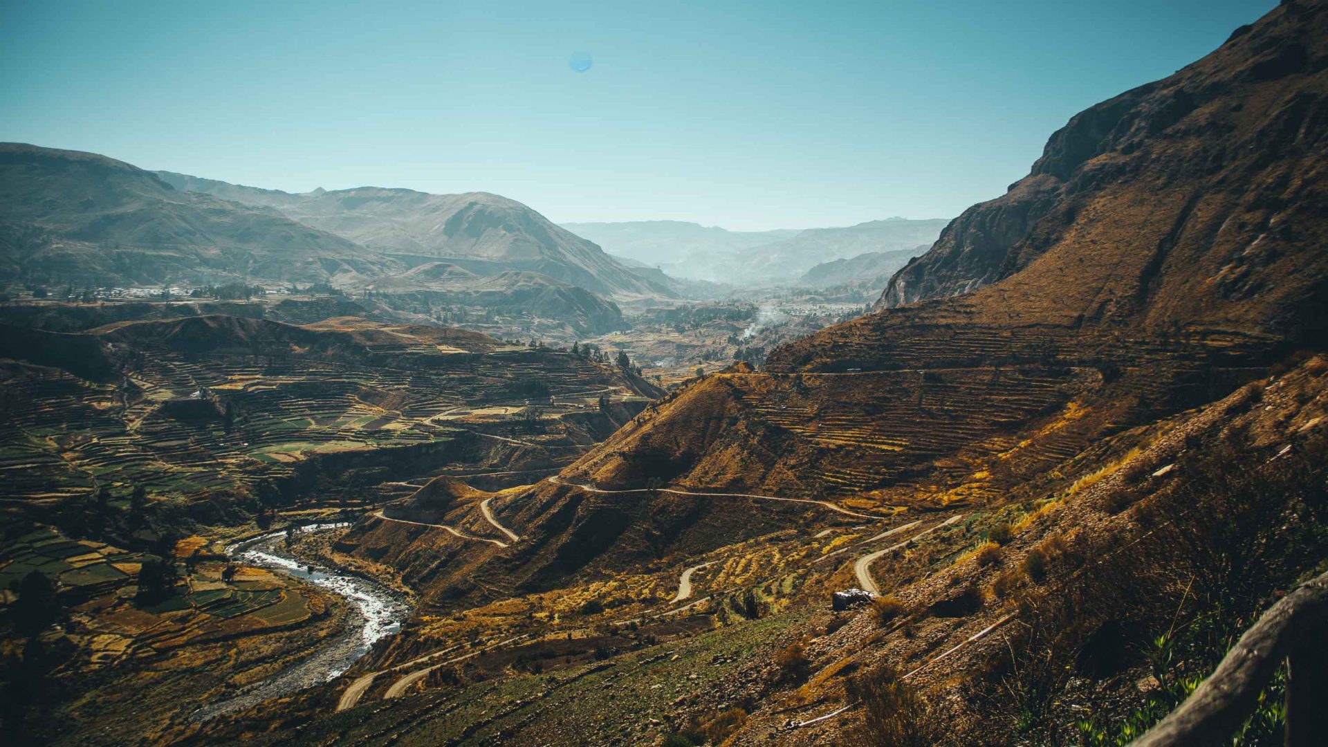 The steep walls of a canyon with a road at the bottom.