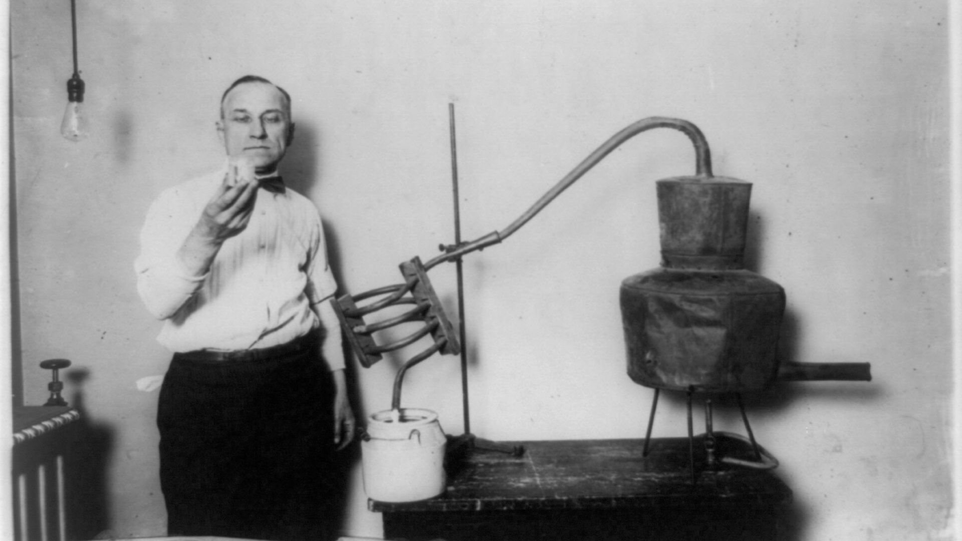 A man holds up a glass of moonshine.