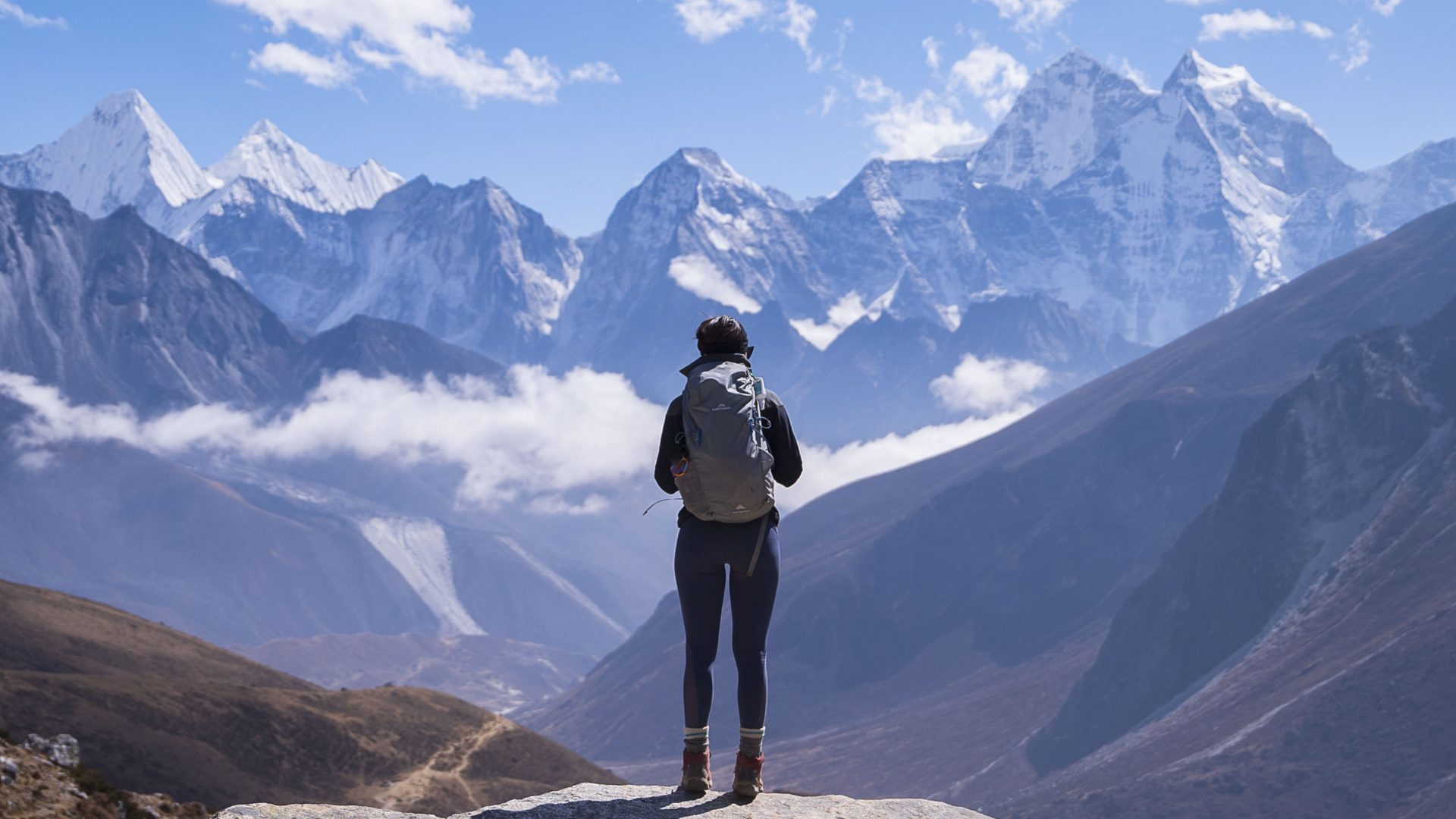 One woman looks out over snow covered mountains.