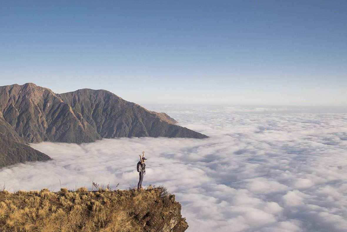 A solitary figure looks out over the clouds while hiking to Mount Everest Base Camp.