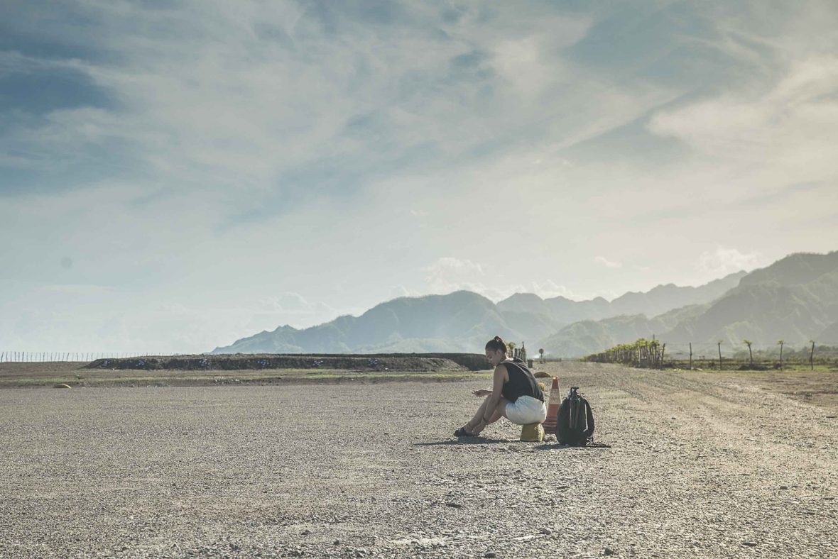 A girl sits on the dusty ground in East Timor looking defeated.