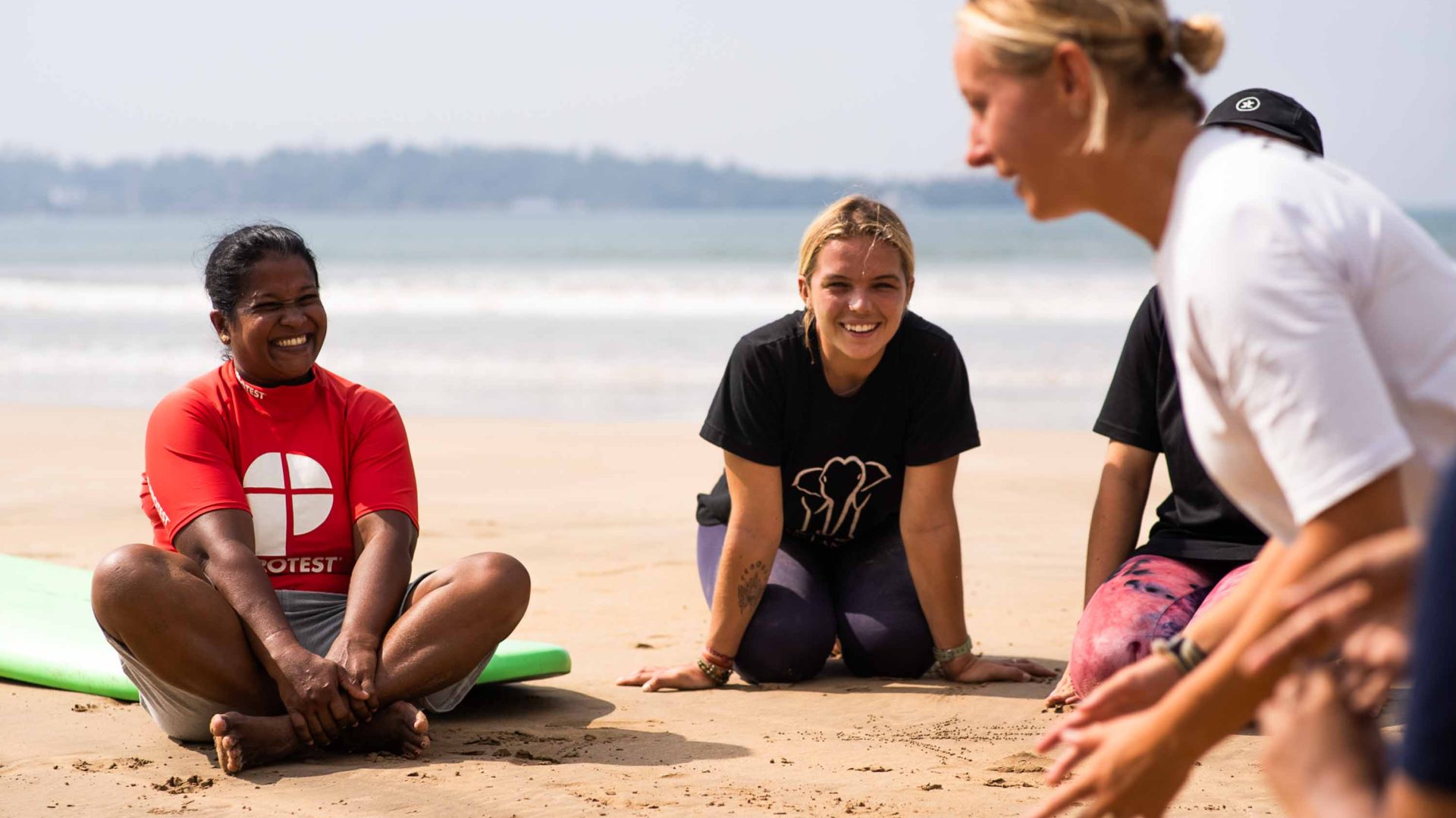 A woman gives surf lessons on the sand.