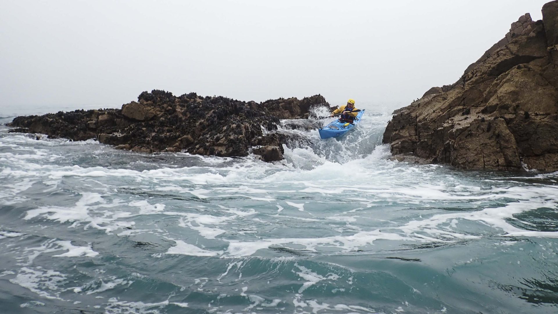 A man kayaks through waves.