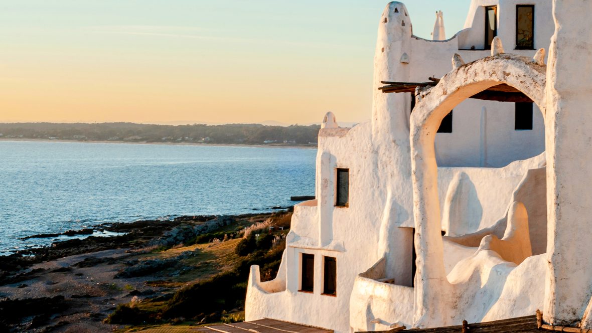 A white building on the edge of a lake.