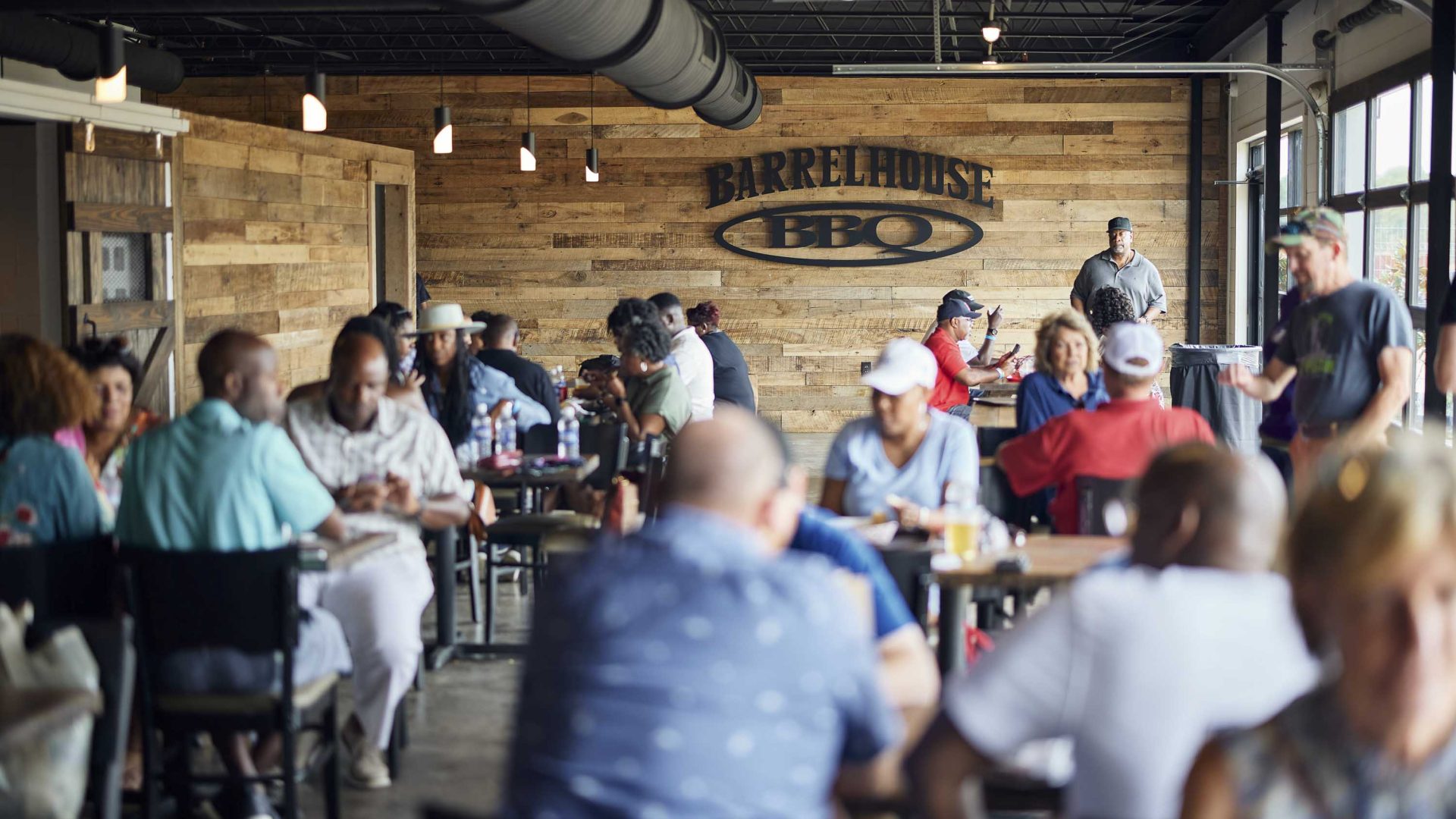 People sit at tables inside a wood panelled barrel house.