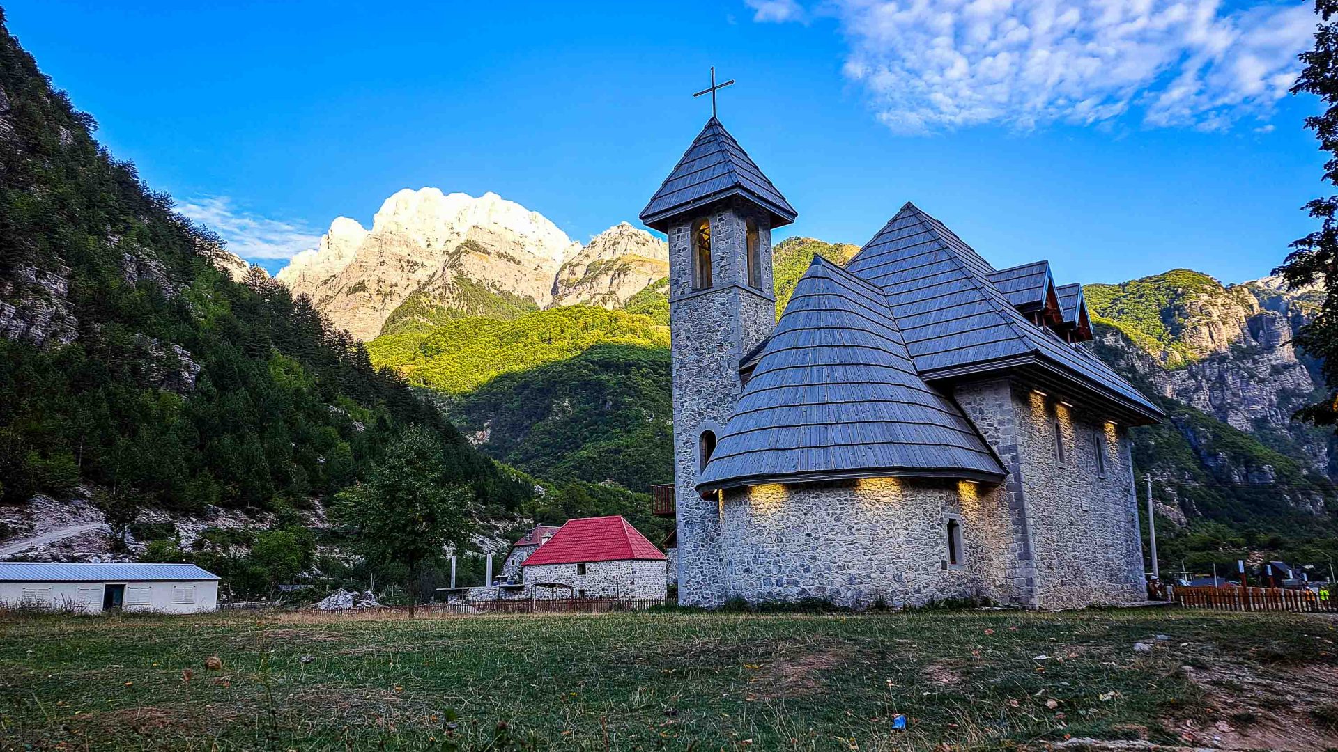 A traditional building in a valley with mountains behind it.