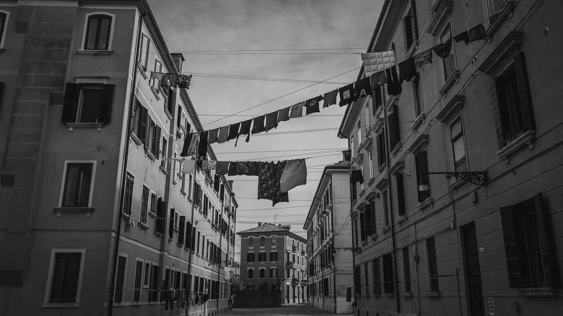 Washing hangs from lines over the street, connecting two buildings.