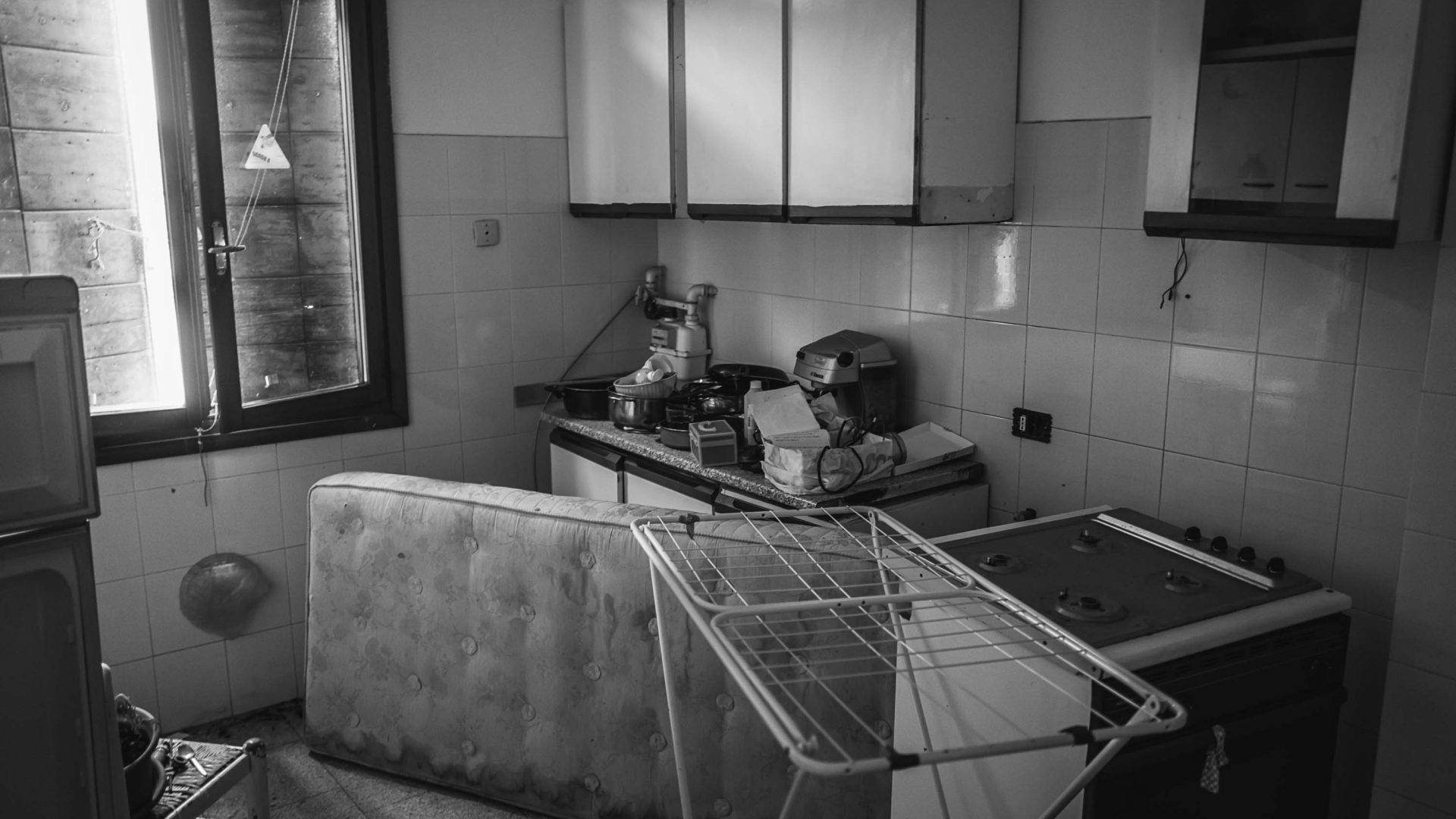 A room with an upturned mattress and clothes hanger. The room is in disarray.