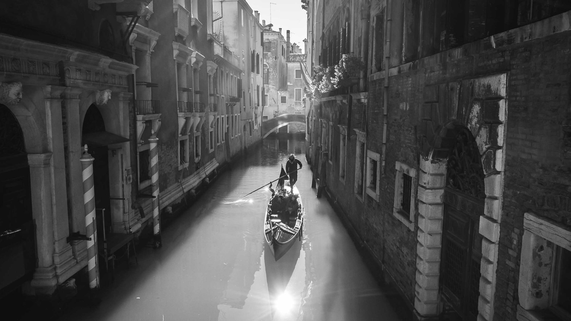 A gondolier takes his gondola down a canal in Venice.