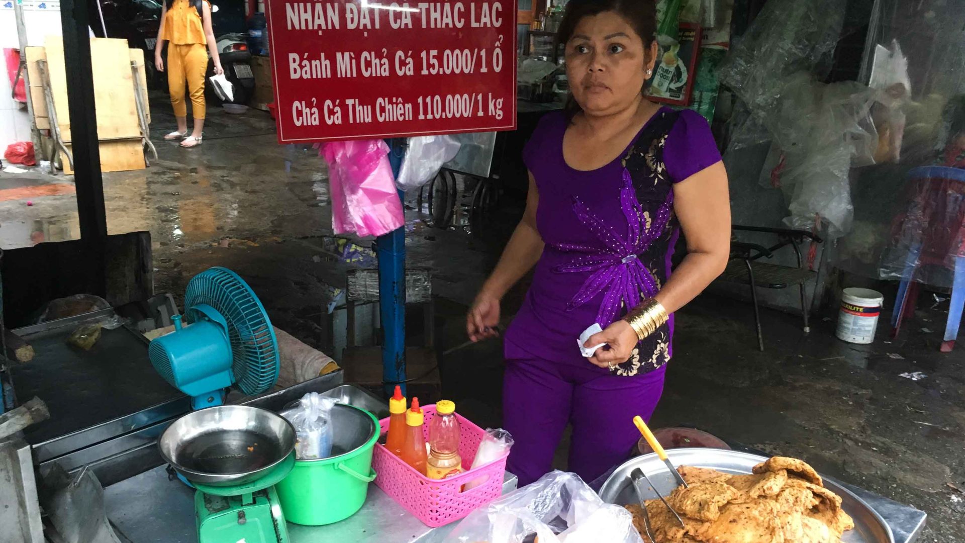 A woman prepares fish bahn mi at her stall.