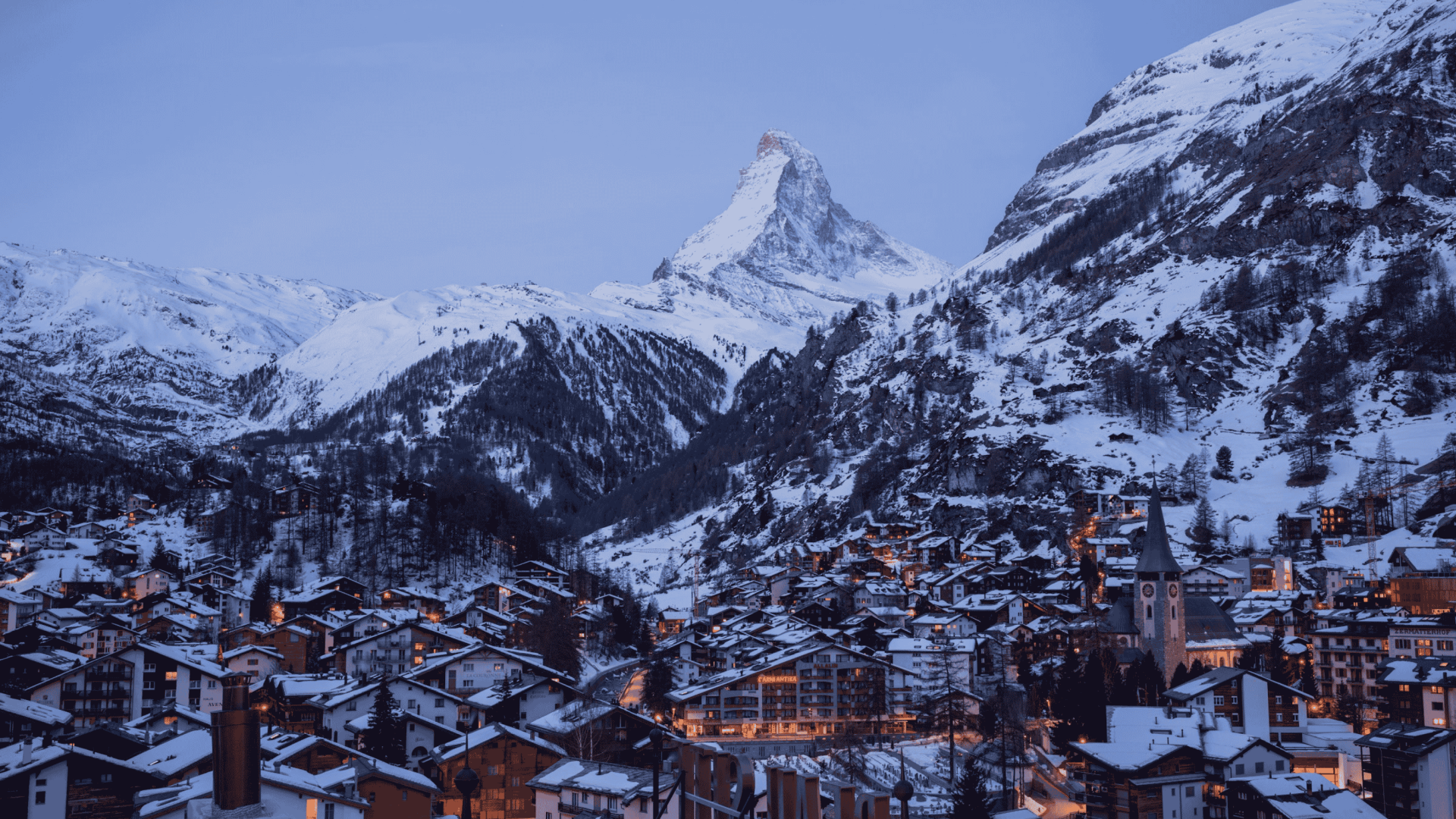 A view of the Matterhorn in Zermatt, Switzerland, at night, with the city in the foreground.